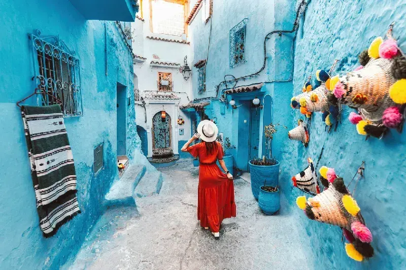 Young woman with red dress visiting the blue city Chefchaouen