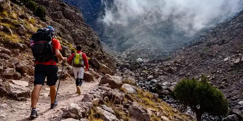 Turista haciendo senderismo hacia la cima del Jabal Toubkal, la montaña más alta de la cordillera del Atlas.