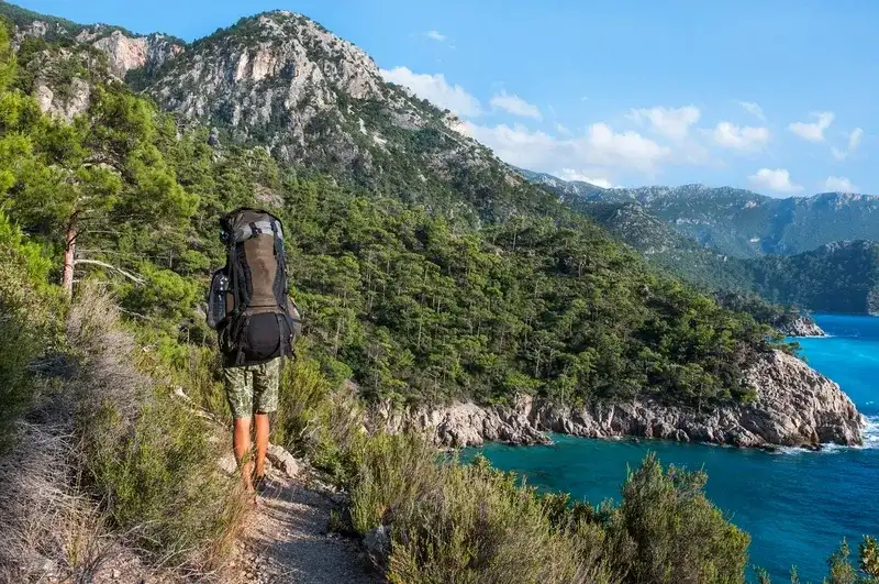 Backpacker hiking a coastal trail above turquoise sea on the Lycian Way in Turkey