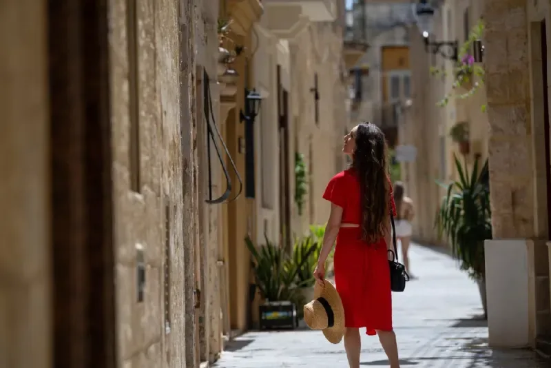Joven mujer con vestido rojo explorando las coloridas y estrechas calles del casco antiguo de Rabat