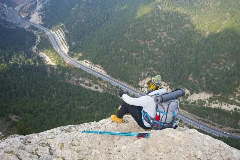 Traveller with backpack enjoying nature on peak of mountain