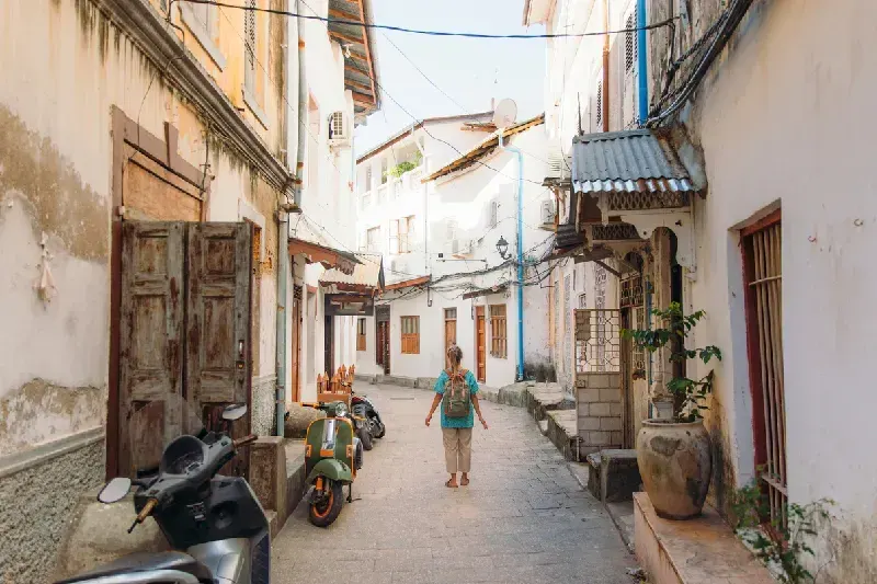 Young woman walking at the old street of Stone Town 