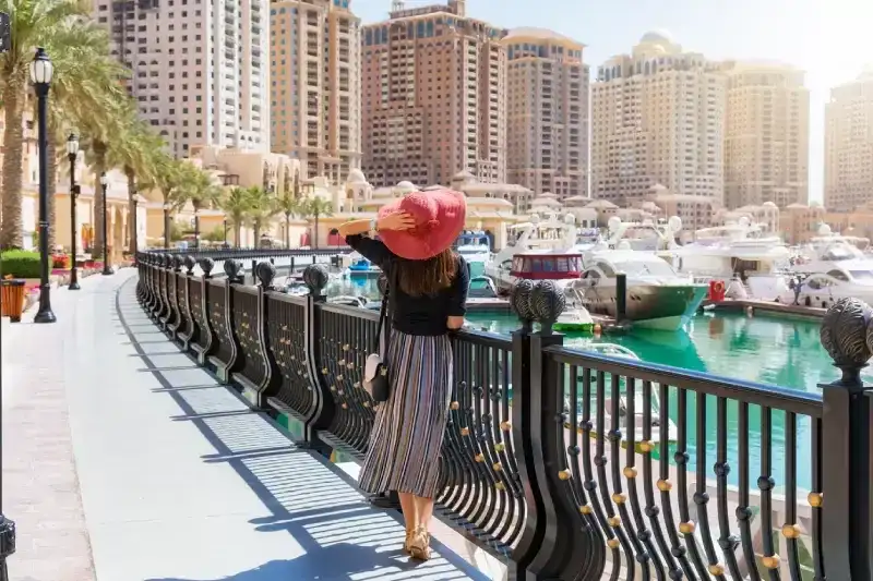 Elegant woman looks at the Marina Walkway in Porto Arabia at the Pearl in Doha, Qatar