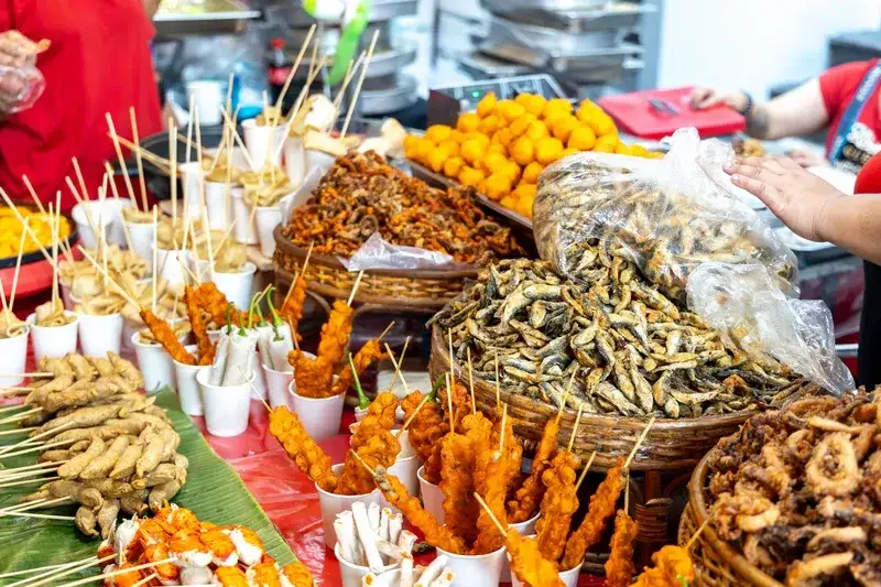 street-food-stall-displaying-assorted-fried-snacks-including-skewered-meats-fish-balls-crispy-fried-fish-and-tempura-in-baskets-and-cups-philippines