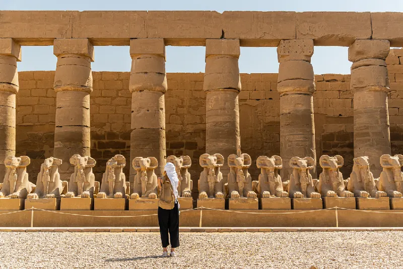 Turista caminando por el templo de Karnak, en Luxor, entre la avenida de las esfinges de Tebas.