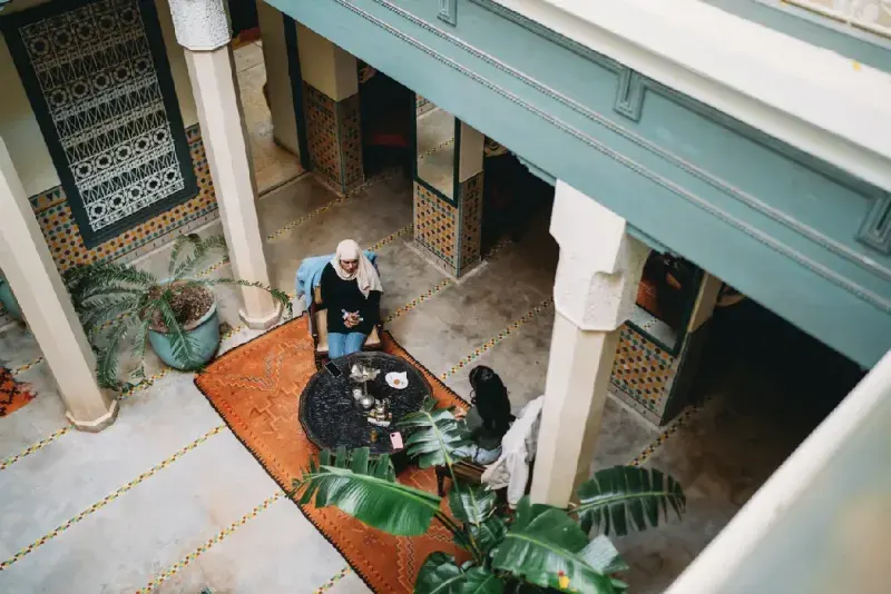 Mujeres con hijab disfrutando té en el patio de un riad en Marrakech