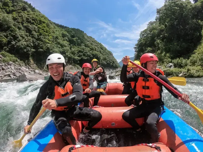 grupo-de-pessoas-sorrindo-durante-rafting-no-rio-yoshino-no-desfiladeiro-de-oboke-koboke-vale-de-iya-shikoku-japao-cercado-por-montanhas-cobertas-de-vegetacao