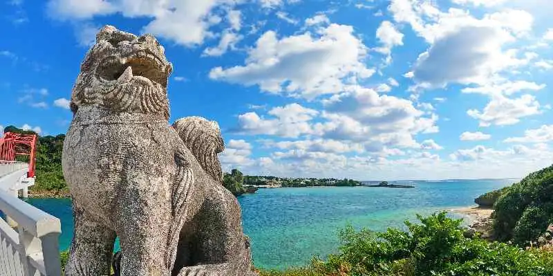 Mare di Okinawa e statua Shisa sotto il cielo azzurro con il Ponte Ikei