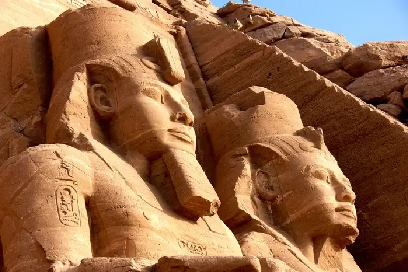 Ägyptische Pyramiden und antike Statuen im warmen Licht des Sonnenuntergangs.