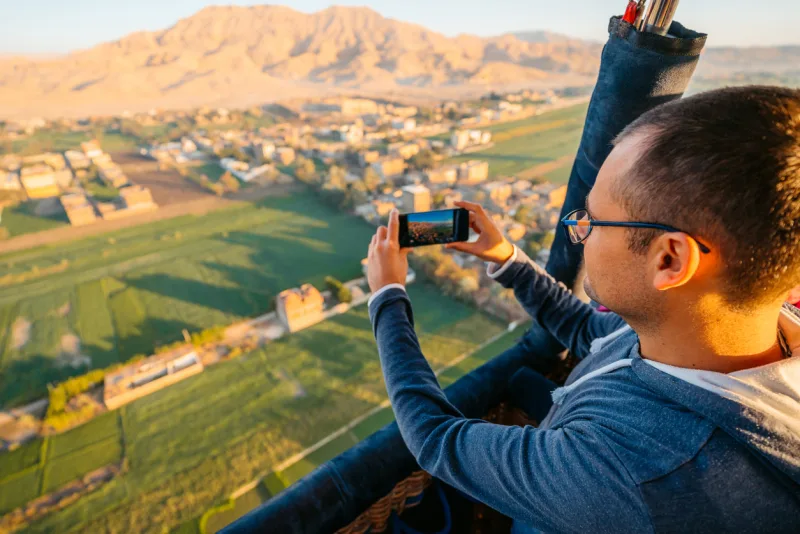 Man taking picture using phone from the hot air baloon in Luxor, hot air balloon ride Luxor