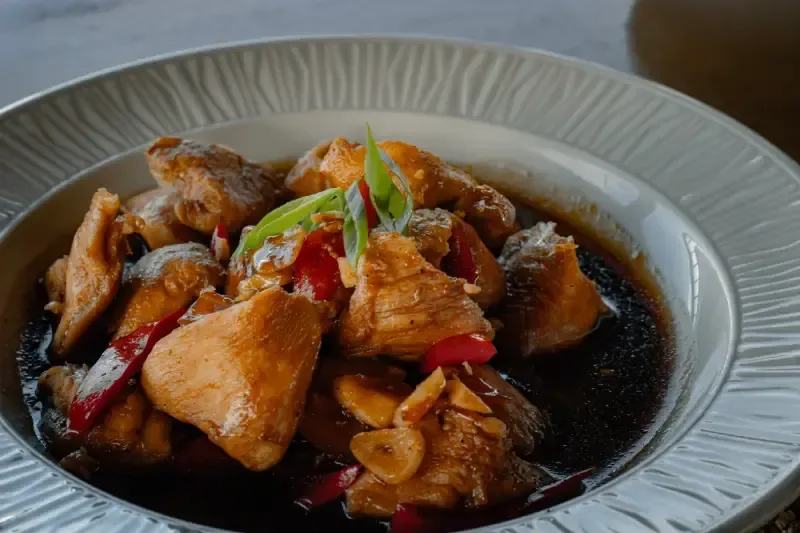 filipino-chicken-adobo-braised-in-dark-soy-sauce-with-garlic-red-chili-slices-and-spring-onion-garnish-served-in-a-textured-ceramic-bowl