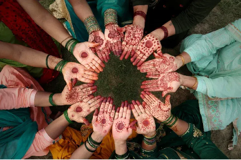 Women showing traditional henna designs on their hands.