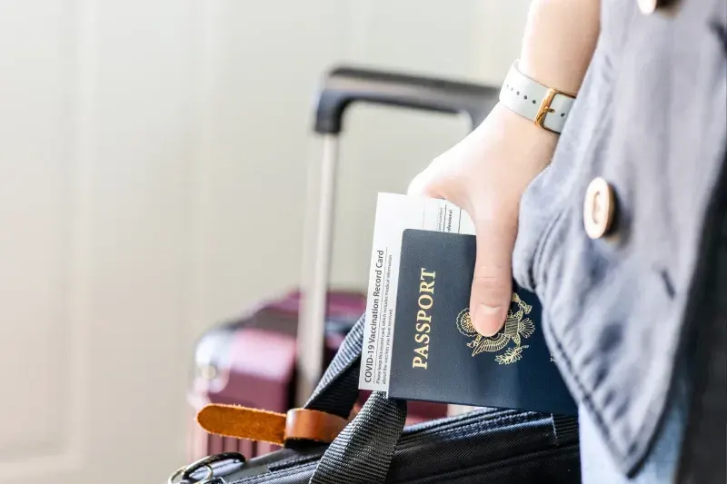 Person mit US-Ausweis, Impfbescheinigung, Reisepass und persönlichen Gegenständen bereit für die Reise