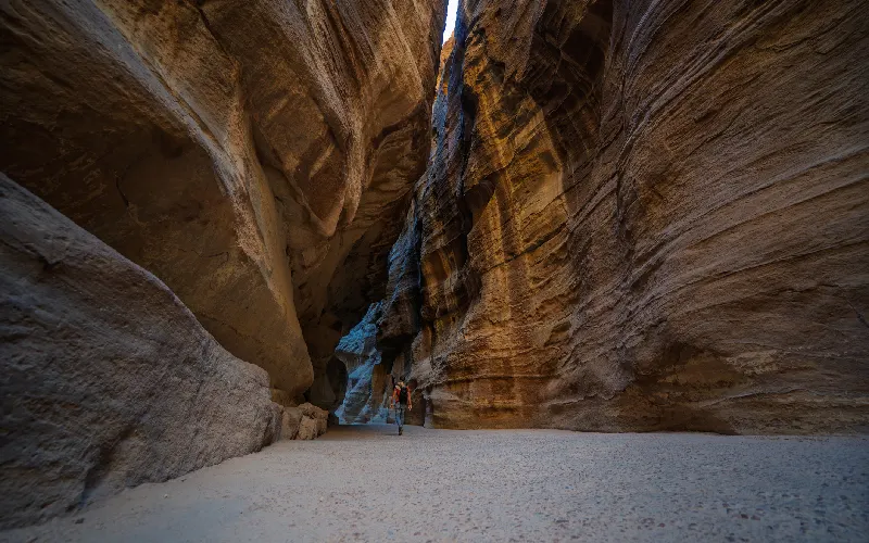 Lone tourist walking through the narrow Siq canyon in Petra, Jordan