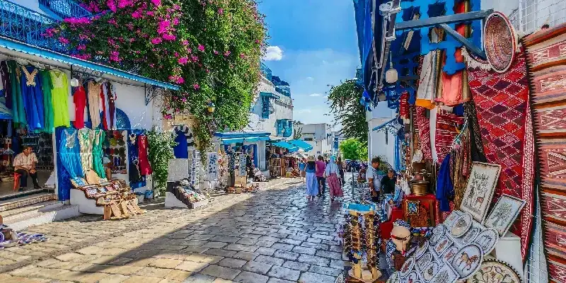 Calle principal comercial con turistas paseando en una ciudad blanca y azul. Norte de África.