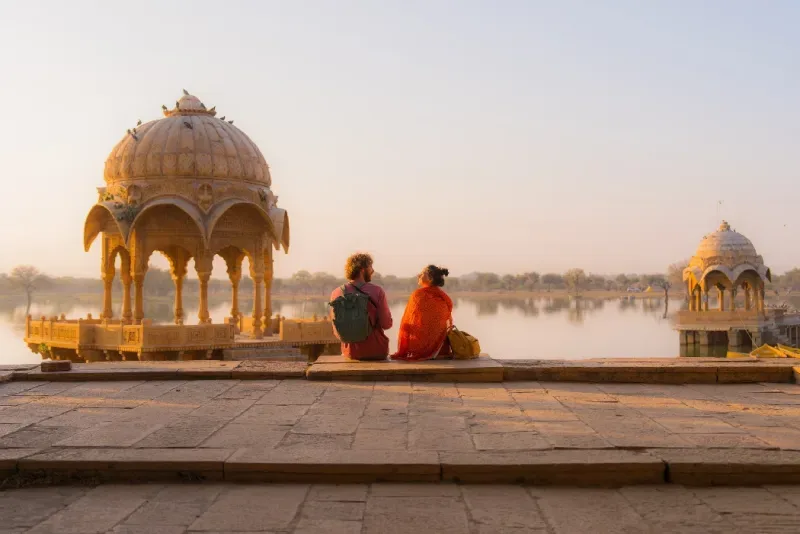 Un hombre y una mujer disfrutan de una hermosa puesta de sol en el lago Gadisar, en Jaisalmer, India.