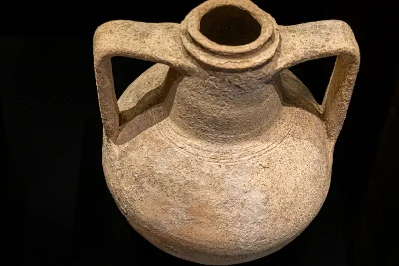 Antica brocca di terracotta  per bere vino su sfondo nero.