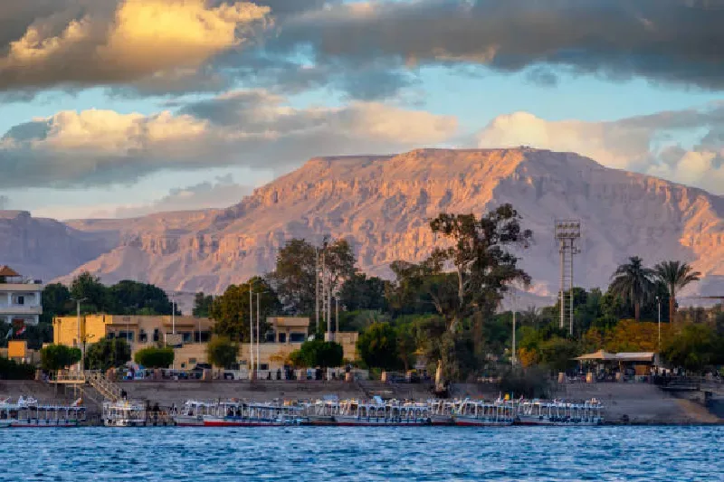 Traditionelle Feluccas am Ufer des Nils in Luxor, Ägypten, mit Sonnenuntergang im Hintergrund