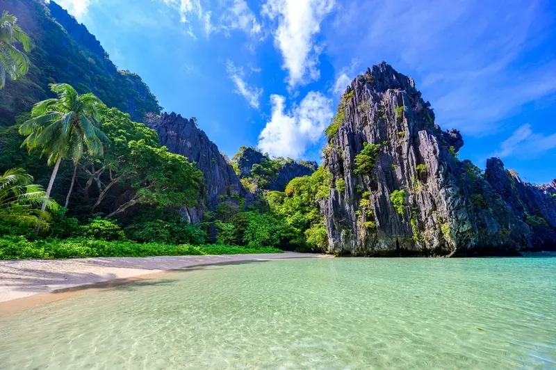secluded-white-sand-beach-with-crystal-clear-turquoise-water-framed-by-towering-limestone-in-el-nido-palawan-philippines