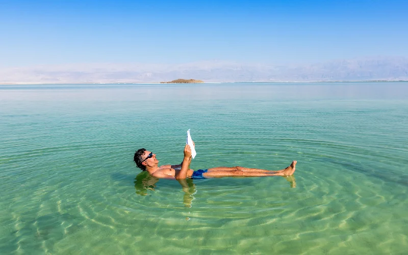 Man relaxing in nature.. View of Dead Sea coastline. Salt crystals at sunset. Texture of Dead sea. Salty sea