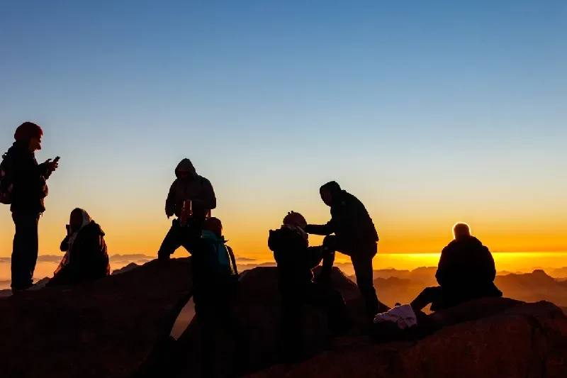 Menschen beobachten den Sonnenaufgang auf dem Gipfel des Berges Sinai (Mosesberg) in Ägypten