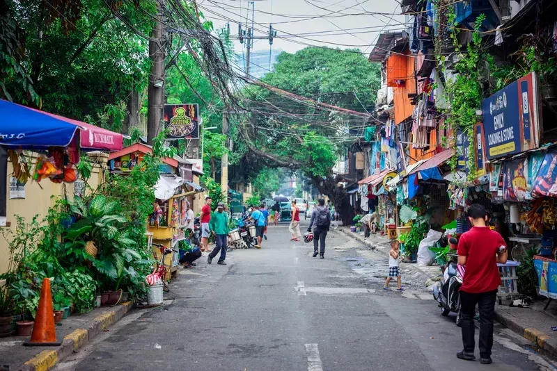 busy-neighborhood-street-in-manila-lined-with-small-shops-food-stalls-and-tangled-overhead-wires