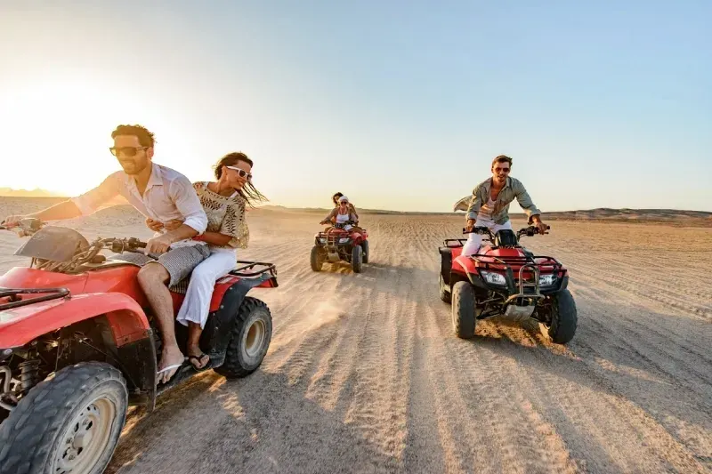 Gruppo di amici fa un'escursione in quad nel deserto durante una calda e memorabile giornata estiva