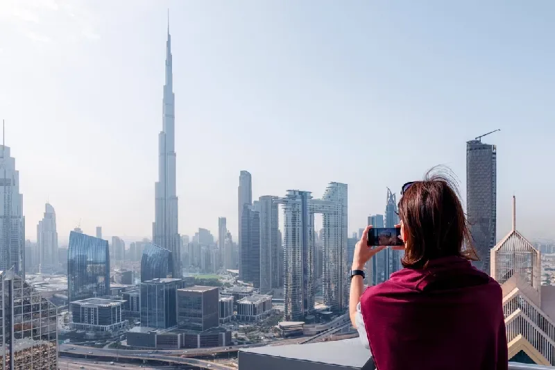Frau fotografiert die moderne Skyline von Dubai mit dem Burj Khalifa im Hintergrund
