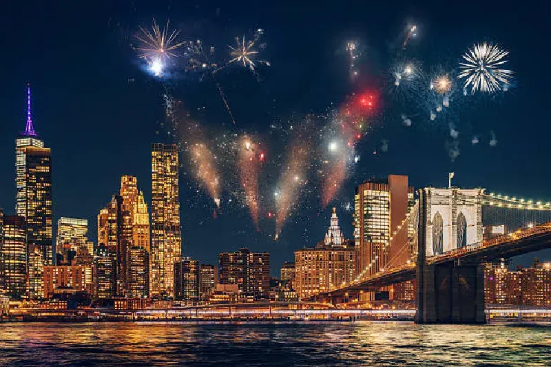 Leuchtendes Feuerwerk über der Brooklyn Bridge in New York City bei Nacht, mit funkelnden Lichtern, die die Skyline von Manhattan über dem East River erhellen.