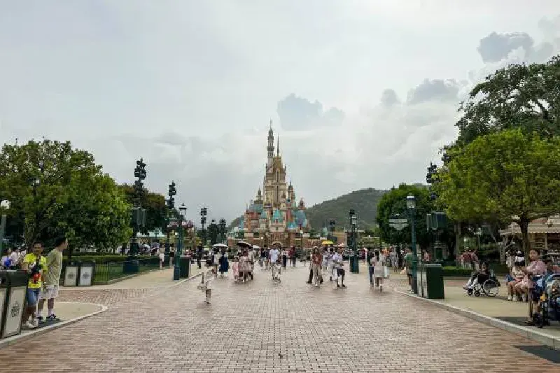 Besucher im Hong Kong Disneyland Resort vor dem Schloss der Magischen Träume im zentralen Bereich, umgeben von bunten Dekorationen und Parkattraktionen.