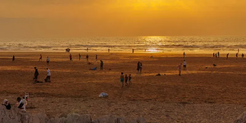 Turistas y residentes locales disfrutan de la playa de Ain Diab al atardecer en Casablanca, Marruecos.