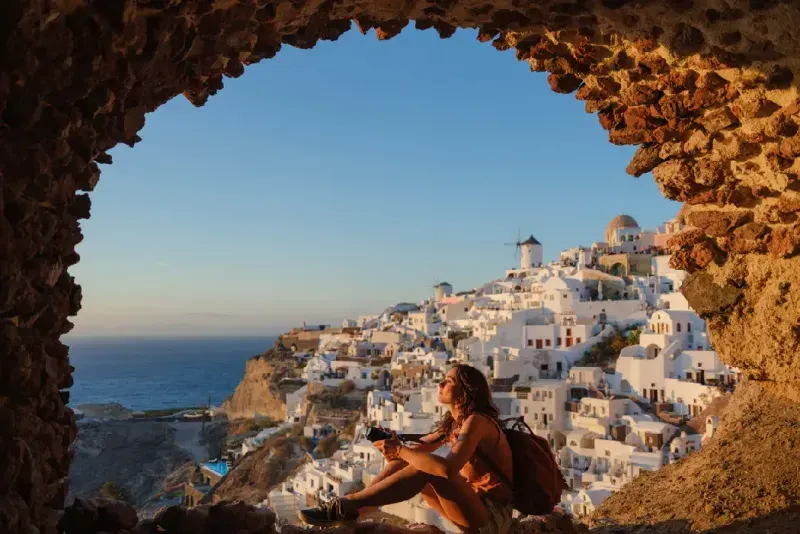 Mujer con cámara mirando con asombro en Oia, Santorini.