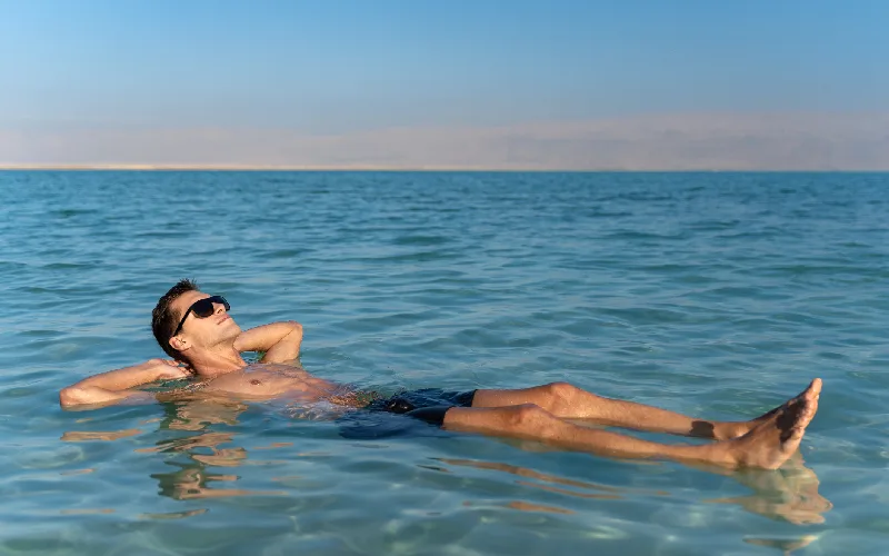 Young man floating on the water surface of the dead sea