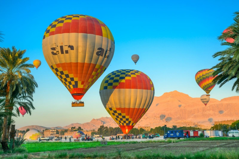 Colorful hot air baloons fly over a desert in Luxor, hot air balloon ride Luxor