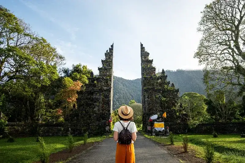 Eine Touristin mit Rucksack genießt einen Spaziergang durch einen Hindu-Tempel während ihres Urlaubs in Asien. 