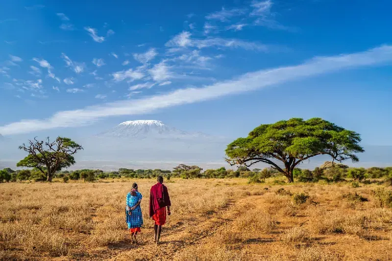 A Maasai family walking across Kenya’s savannah with Mount Kilimanjaro behind them