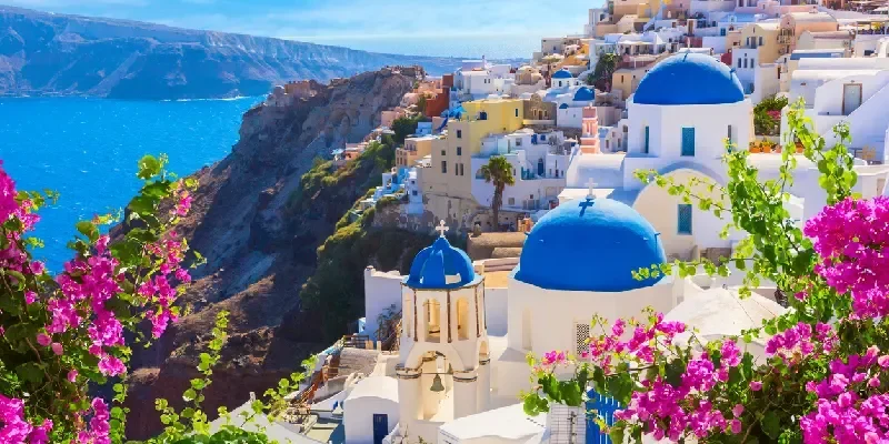 Isla de Santorini, Grecia. Pueblo de Oia con casas tradicionales blancas e iglesias con cúpulas azules sobre la caldera, mar Egeo.