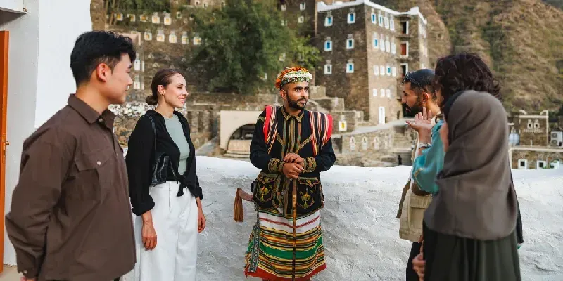 Guía turístico con visitantes explorando la historia y arquitectura tradicional de Rijal Almaa.