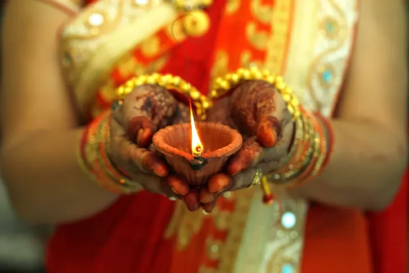 Mujer india sosteniendo una lámpara de aceite de Diwali.