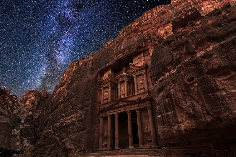 Die antike Stadt Petra in Jordanien, beleuchtet unter einem klaren, sternenübersäten Nachthimmel