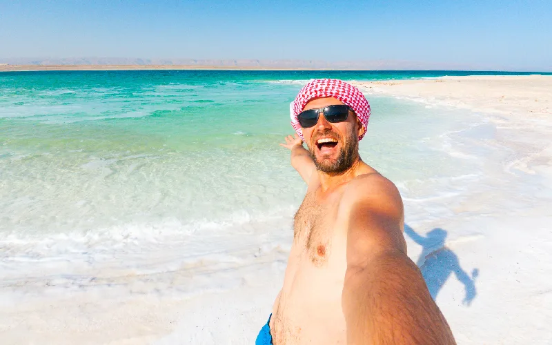 Happy male traveler tourist taking a smartphone selfie at the Dead Sea in Jordan