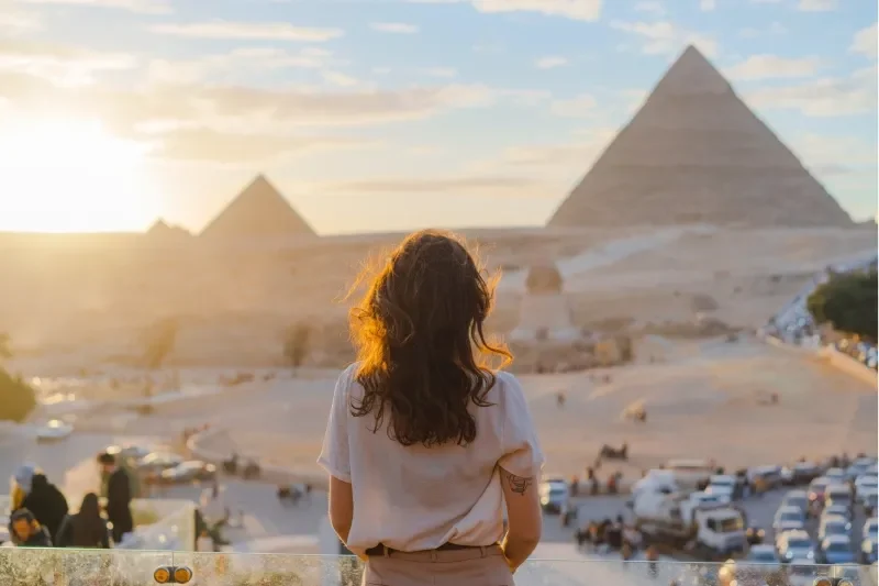 Giovane donna in piedi sulla terrazza con le piramidi di Giza sullo sfondo.
