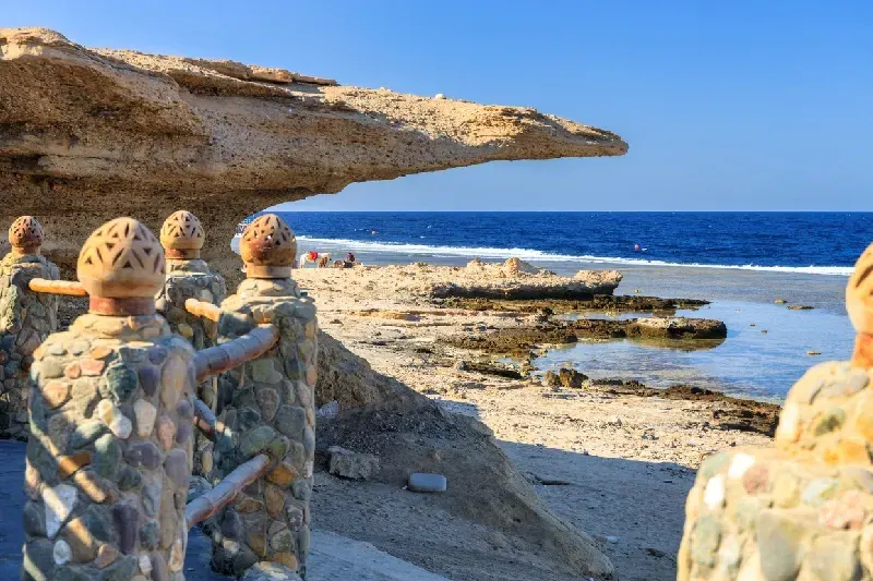 Felsiger Küstenstrand mit tiefblauem Meer unter klarem blauem Himmel.