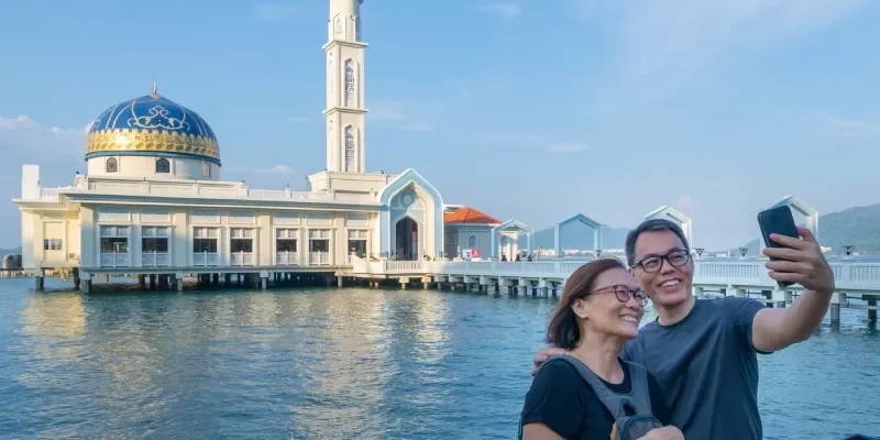 Pareja tomándose selfies frente a una mezquita flotante