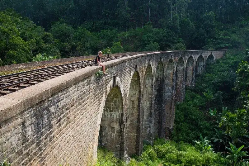 A woman admiring the view from the Nine Arch Bridge in Ella,