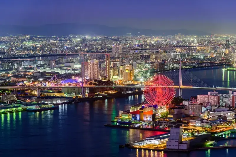 cidade-de-osaka-iluminada-a-noite-com-canal-roda-gigante-e-edificios-refletidos-na-agua