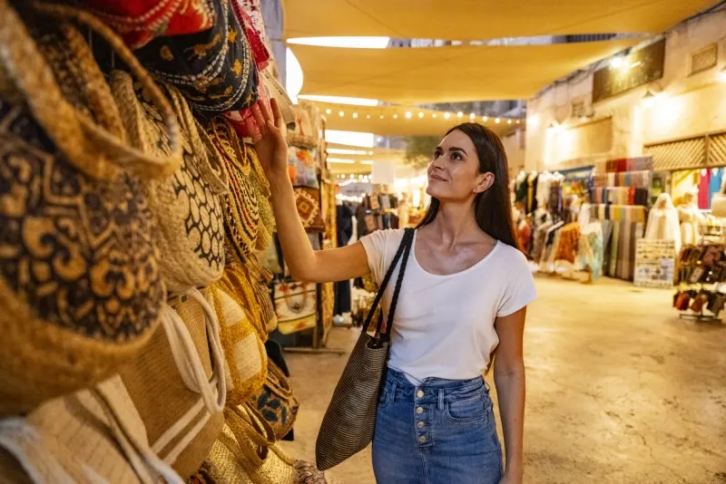 Mid adult female tourist looking at bags in Dubai souk