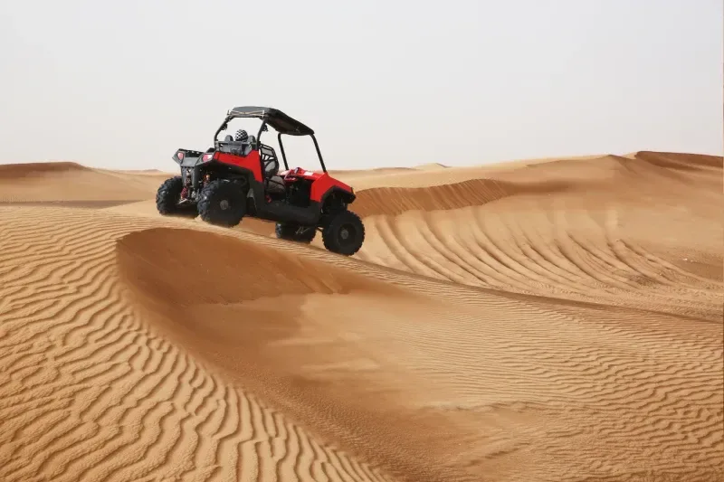 Geländewagen fährt mit hoher Geschwindigkeit durch Sanddünen in der arabischen Wüste