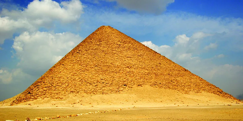 The Red Pyramid at Dahshur, Egypt, showcased under a clear sky, highlighting its massive limestone structure and historical significance as one of Egypt’s earliest smooth-sided pyramids.