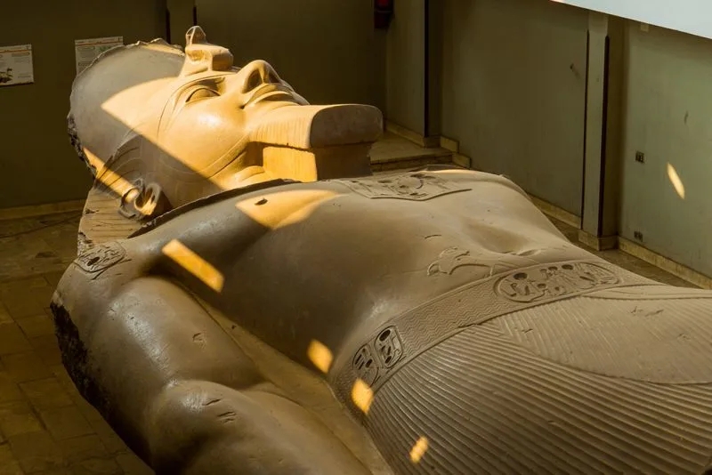 sun rays fall on giant statue of Ramses II's face, City of Memphis